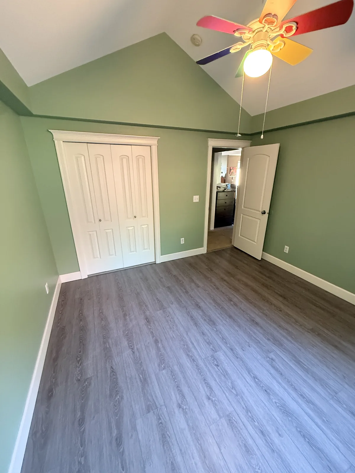 Bedroom with new gray wood-look vinyl plank floor, white baseboards, and white closet doors